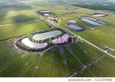 Water ponds for farm cattle. Drink source for cows grazing in pasture fields. Green industrial farm grassland in Florida Water ponds for farm cattle. Drink source for cows grazing in pasture fields. Green industrial farm grassland in Florida 121204988