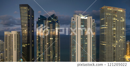 View from above of brightly illuminated high skyscraper buildings in downtown district of Sunny Isles Beach city in Florida, USA. American tourist urban district at night 121205022