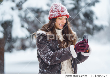 Cute woman enjoying the snowy landscape in the park. Concept of nature, technology. Cute woman enjoying the snowy landscape in the park. Concept of nature, technology. 121205373
