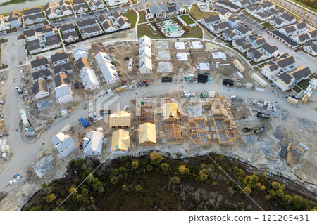 Unfinished frames of inexpensive homes with wooden roof beams under construction. Development of residential housing in US suburbs. Real estate market in the USA Unfinished frames of inexpensive homes with wooden roof beams under construction. Development of residential housing in US suburbs. Real estate market in the USA 121205431