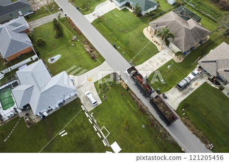 Top view of Hurricane Ian special aftermath recovery dump truck picking up tree branches debris from Florida rural streets. Dealing with consequences of natural disaster 121205456