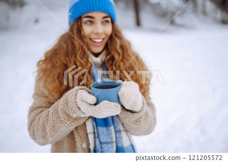 Smiling woman with a thermos in a snowy forest enjoying nature. Adventure concept. Lifestyle. Smiling woman with a thermos in a snowy forest enjoying nature. Adventure concept. Lifestyle. 121205572