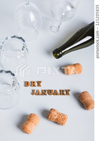 Overturned glasses, empty bottles, corks and text dry january on gray vertical view 121205835
