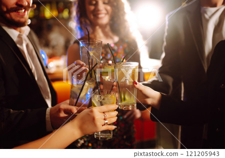 Cheering and drinking cocktails. Group of friends partying in nightclub, toasting drinks cocktails. 121205943
