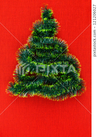 A small christmas tree of tinsel, on a red background A small christmas tree of tinsel, on a red background 121206027
