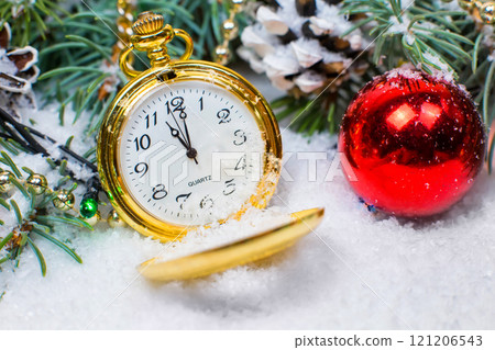A vintage clock in the snow against the background of a Christmas tree and a garland 121206543