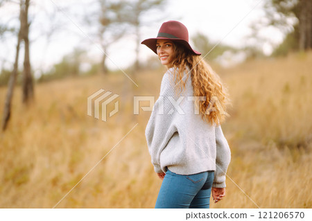 Stylish woman in sweater and hat enjoys autumn nature. People, freedom, lifestyle, travel concept. 121206570