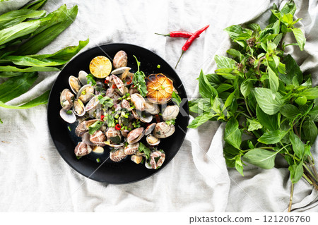 Clams and mussels with garlic and herbs served on a black plate with greens. Clams and mussels with garlic and herbs served on a black plate with greens. 121206760