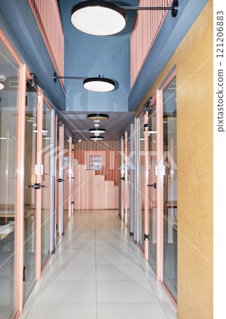 Vertical shot of hallway with glass doors leading to individual office rooms in modern office building decorated with pink design elements, camera flash, copy space Vertical shot of hallway with glass doors leading to individual office rooms in modern office building decorated with pink design elements, camera flash, copy space 121206883