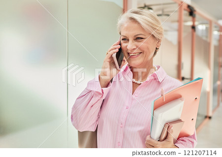 Portrait of smiling mature businesswoman dressed in elegant pink shirt for office work talking on phone in hallway of modern coworking space, copy space 121207114