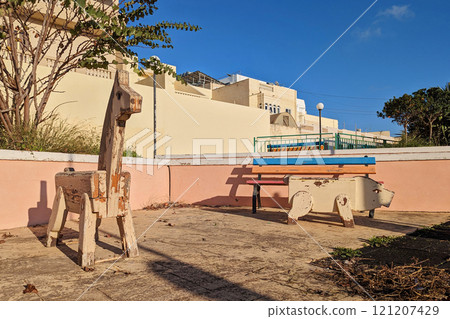Old playground with weathered wooden animal structures in residential area during golden sunset under clear blue sky Old playground with weathered wooden animal structures in residential area during golden sunset under clear blue sky 121207429
