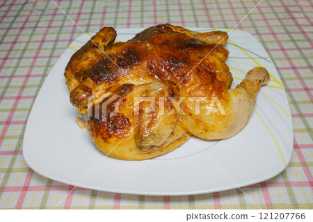 Whole roasted chicken on white plate with plaid tablecloth background Whole roasted chicken on white plate with plaid tablecloth background 121207766