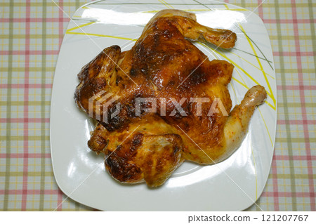 Whole roasted chicken on white plate with plaid tablecloth background 121207767
