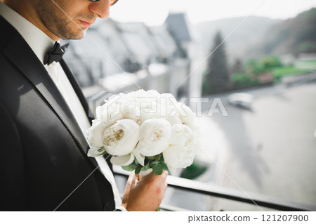Beautiful man, groom holding big and beautiful wedding bouquet with flowers Beautiful man, groom holding big and beautiful wedding bouquet with flowers 121207900