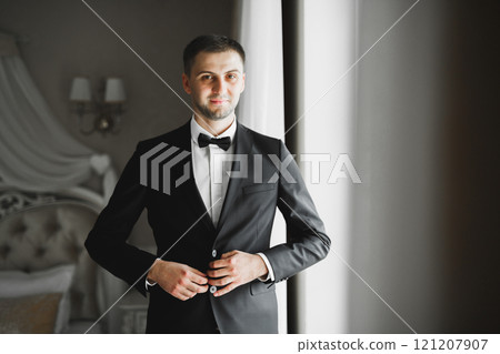 Grooms morning preparation. Handsome man getting dressed and preparing for the wedding Grooms morning preparation. Handsome man getting dressed and preparing for the wedding 121207907