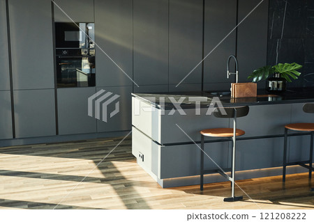 Interior of sunlit kitchen in Scandinavian industrial style boasting functional countertop with sink at center creating comfortable atmosphere for cooking, copy space 121208222