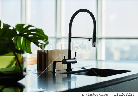 Close up shot of kitchen faucet silhouette mounted on black marble countertop in modern minimalist kitchen, copy space 121208225