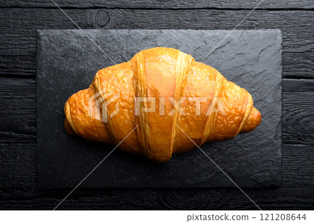Close-up of freshly baked croissant on black plate 121208644