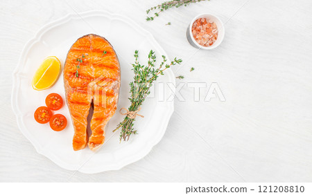 salmon steak on plate with spices thyme baked on a grill on a white background top view. copy space salmon steak on plate with spices thyme baked on a grill on a white background top view. copy space 121208810