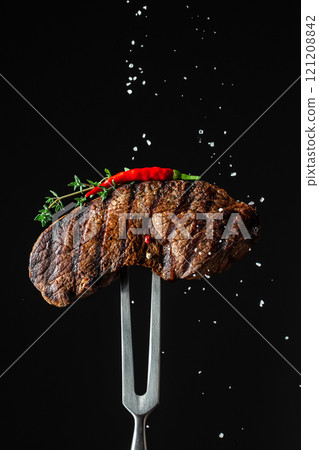 cooking meat steak and adding salt, grilled steak. vertical image. copy space for text 121208842