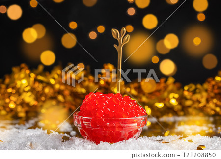 Salmon Red Caviar in bowl on a festive table with defocused Christmas lights at background. Luxury delicacy food, copy space 121208850