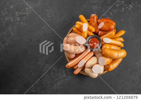 Set of different types of sausages, Boiled meat sausages with ketchup on a dark background. top view. copy space 121208879