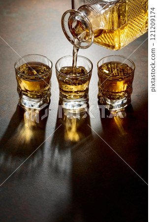 Whiskey poured from a decanter into a small glasses. 121209174