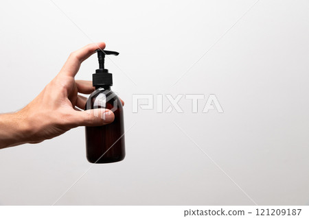 Young woman holding a big plastic bottle with a pump in her hand, on a white background. Caring for clean and soft skin of the body. Daily cosmetic product Young woman holding a big plastic bottle with a pump in her hand, on a white background. Caring for clean and soft skin of the body. Daily cosmetic product 121209187