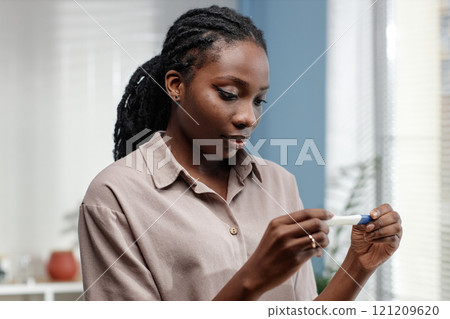 Portrait shot of serious young African American woman holding pregnancy test waiting for result in bathroom, copy space Portrait shot of serious young African American woman holding pregnancy test waiting for result in bathroom, copy space 121209620