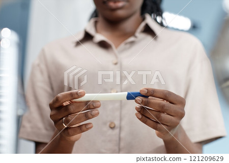 Cropped shot of African American woman holding pregnancy test in hands waiting for result in bathroom, copy space 121209629