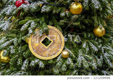 Christmas tree adorned with golden ornaments and large ancient Chinese coin, symbolizing prosperity and wealth 121209996