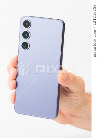 Hand holding modern smartphone with three camera lenses against white background 121210159