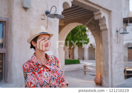 Young woman in an ethnic dress and hat exploring Al Seef Park in Dubai. Surrounded by traditional Emirati architecture and modern vibes, she enjoys the charm of Dubai Creek's cultural heritage. Young woman in an ethnic dress and hat exploring Al Seef Park in Dubai. Surrounded by traditional Emirati architecture and modern vibes, she enjoys the charm of Dubai Creek's cultural heritage. 121210229