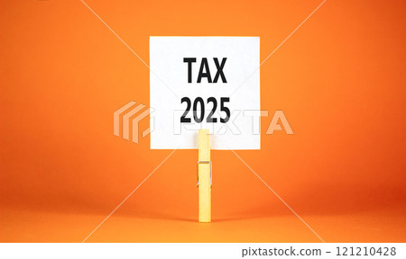 Planning tax 2025 new year symbol. Concept words Tax 2025 on beautiful white paper on wooden clothespin. Beautiful orange background. Business tax 2025 new year concept. Copy space. 121210428