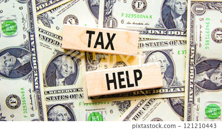 Tax help symbol. Concept words Tax help on wooden blocks on a beautiful background from dollar bills. Dollar bills. Business, support and tax help concept. Copy space. Tax help symbol. Concept words Tax help on wooden blocks on a beautiful background from dollar bills. Dollar bills. Business, support and tax help concept. Copy space. 121210443