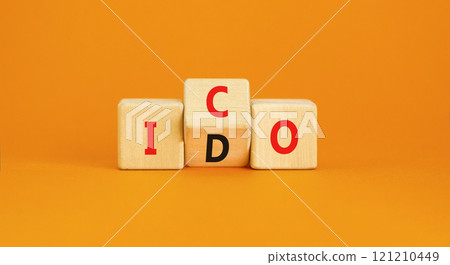 Initial coin or DEX offering symbol. Concept words abbreviation ICO or IDO on wooden block. Beautiful orange table orange background. Business Initial coin or DEX offering concept. Copy space. 121210449