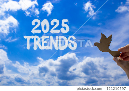 Planning 2025 trends new year symbol. Concept words 2025 Trends on beautiful blue sky. Beautiful blue sky clouds background. Hand holds wooden bird. Business 2025 trends new year concept. Copy space. Planning 2025 trends new year symbol. Concept words 2025 Trends on beautiful blue sky. Beautiful blue sky clouds background. Hand holds wooden bird. Business 2025 trends new year concept. Copy space. 121210597
