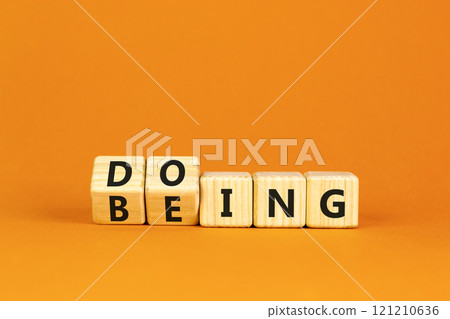 Doing or being symbol. Concept word Doing and Being on wooden cubes. Beautiful orange table orange background. Business doing or being concept. Copy space. Doing or being symbol. Concept word Doing and Being on wooden cubes. Beautiful orange table orange background. Business doing or being concept. Copy space. 121210636