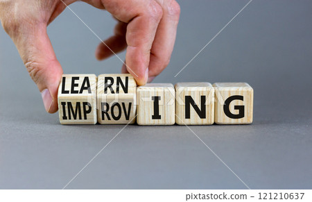 Improving or learning symbol. Businessman turns wooden cubes and changes the word Improving to Learning . Beautiful grey background. Educational business improving or learning concept. Copy space. Improving or learning symbol. Businessman turns wooden cubes and changes the word Improving to Learning . Beautiful grey background. Educational business improving or learning concept. Copy space. 121210637
