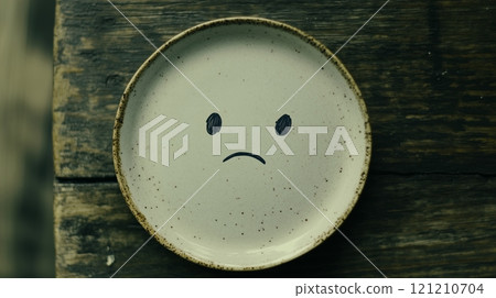 Photo of a face drawn on an empty plate with copy space. 121210704