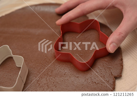 Christmas homemade baking, close-up woman hand cuts out dough for baking gingerbread 121211265