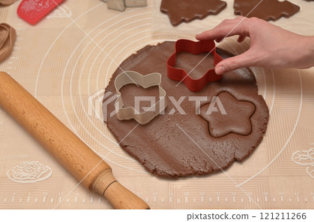 Christmas homemade baking, woman hand cuts out dough for baking gingerbread, cutter, rolling pin, spatula on the table 121211266