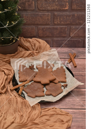 Christmas homemade baking, gingerbread cookies with spices on the wooden table, tree near brick wall, cloth on a background Christmas homemade baking, gingerbread cookies with spices on the wooden table, tree near brick wall, cloth on a background 121211268