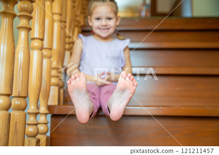Closeup of infant toddler feet, child sitting on stairs at home. Focus on feet Closeup of infant toddler feet, child sitting on stairs at home. Focus on feet 121211457
