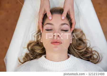 Top view of healer hands performing by lightly touched access bars therapy on young woman head, stimulating positive change thoughts and emotions. Alternative medicine concept 121211480
