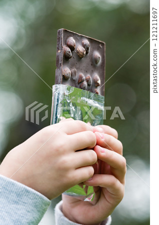 Child's hands holding a partially opened chocolate bar with nuts. Child's hands holding a partially opened chocolate bar with nuts. 121211697