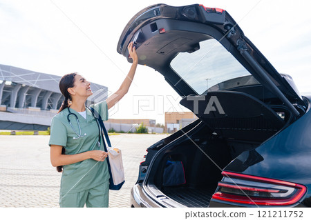 Caucasian female nurse opening the car boot and taking the bag out 121211752