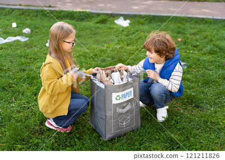 Boy and girl collecting paper garbage in park supporting environmental care in camp 121211826