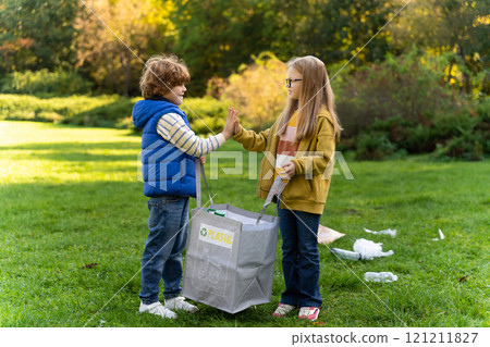 Boy and girl collecting garbage in park supporting environmental care in camp 121211827