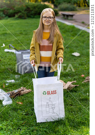 Little girl collecting garbage in park to recycle waste and reduce pollution 121211831